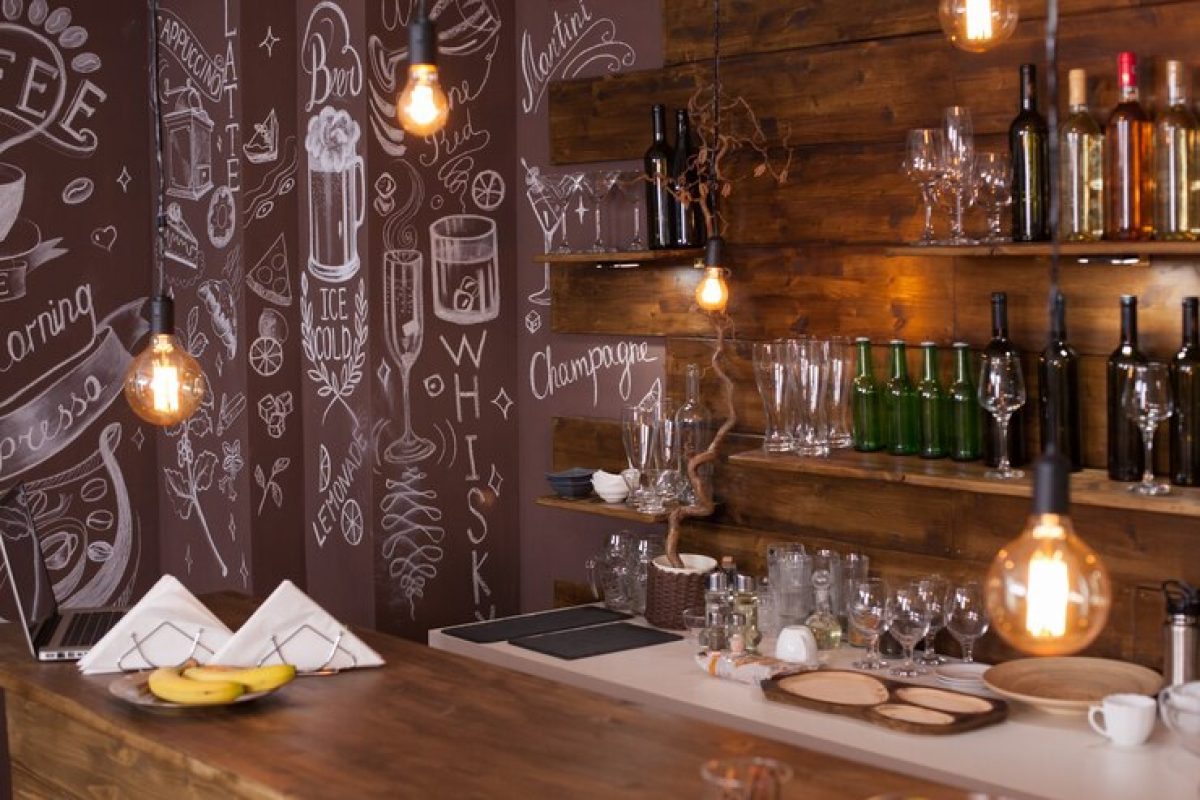 empty-cafe-bar-interior-design-with-artistic-drawing-back-wine-bottles-light-bulbs-hanging-from-ceiling_482257-18253