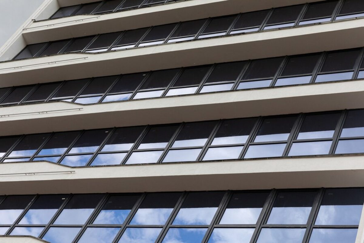 ground-view-glass-square-windows-white-building-facade-with-sky-reflection_88135-11540